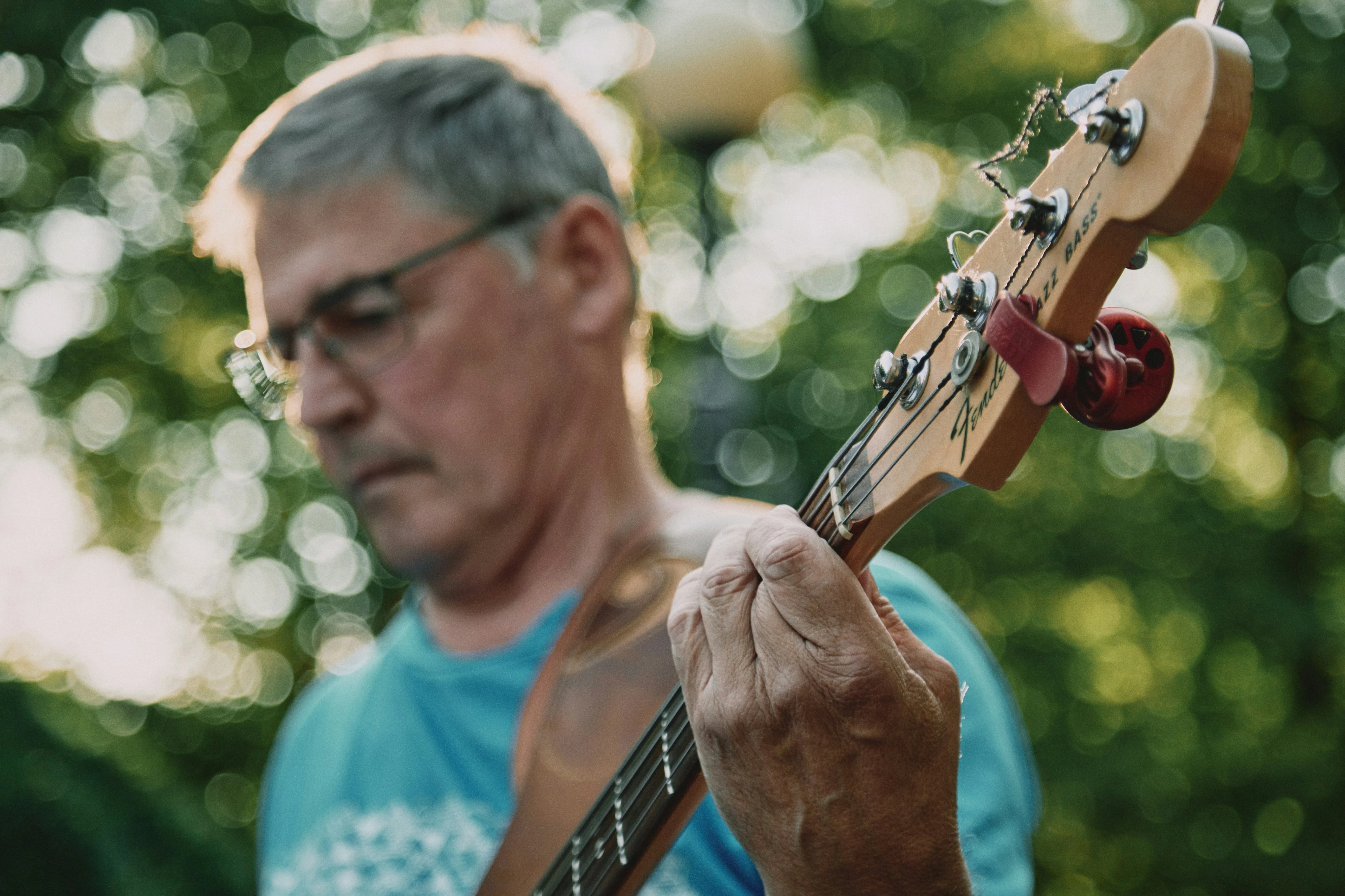 Adult in his 50s playing Fender bass guitar outdoors — learning guitar later in life