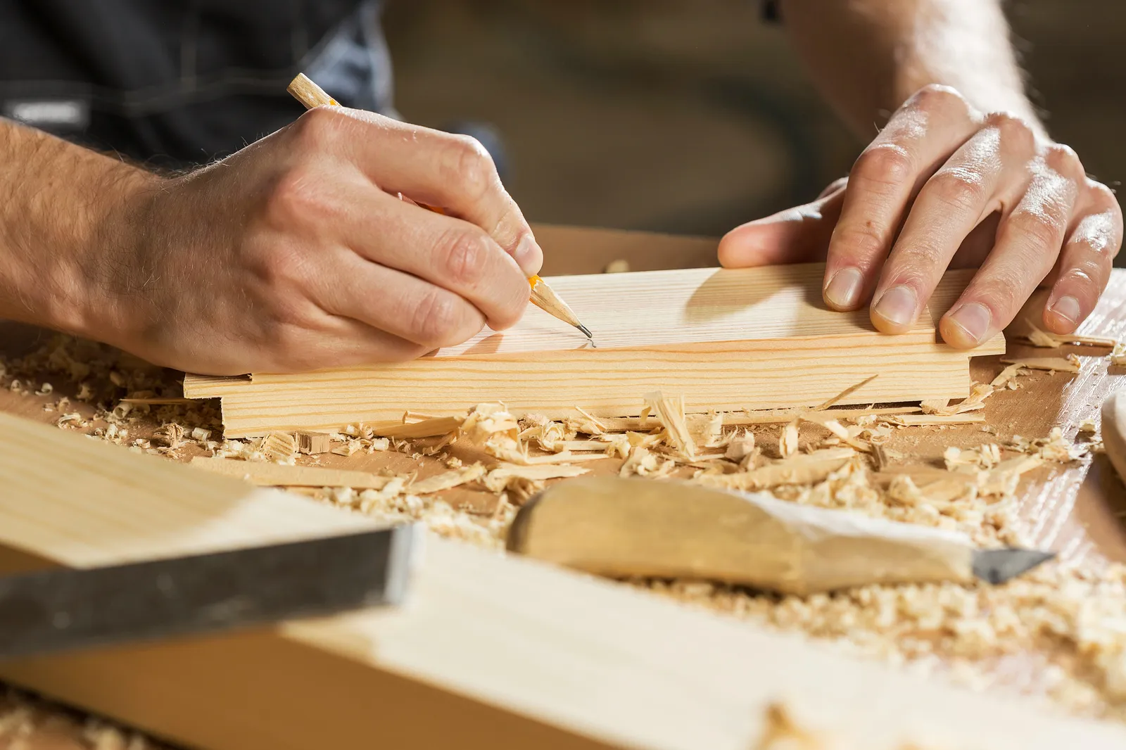 Marking and measuring a guitar body blank by hand at a boutique guitar shop — the kind of design decisions that determine how 'different' a build is from a Stratocaster