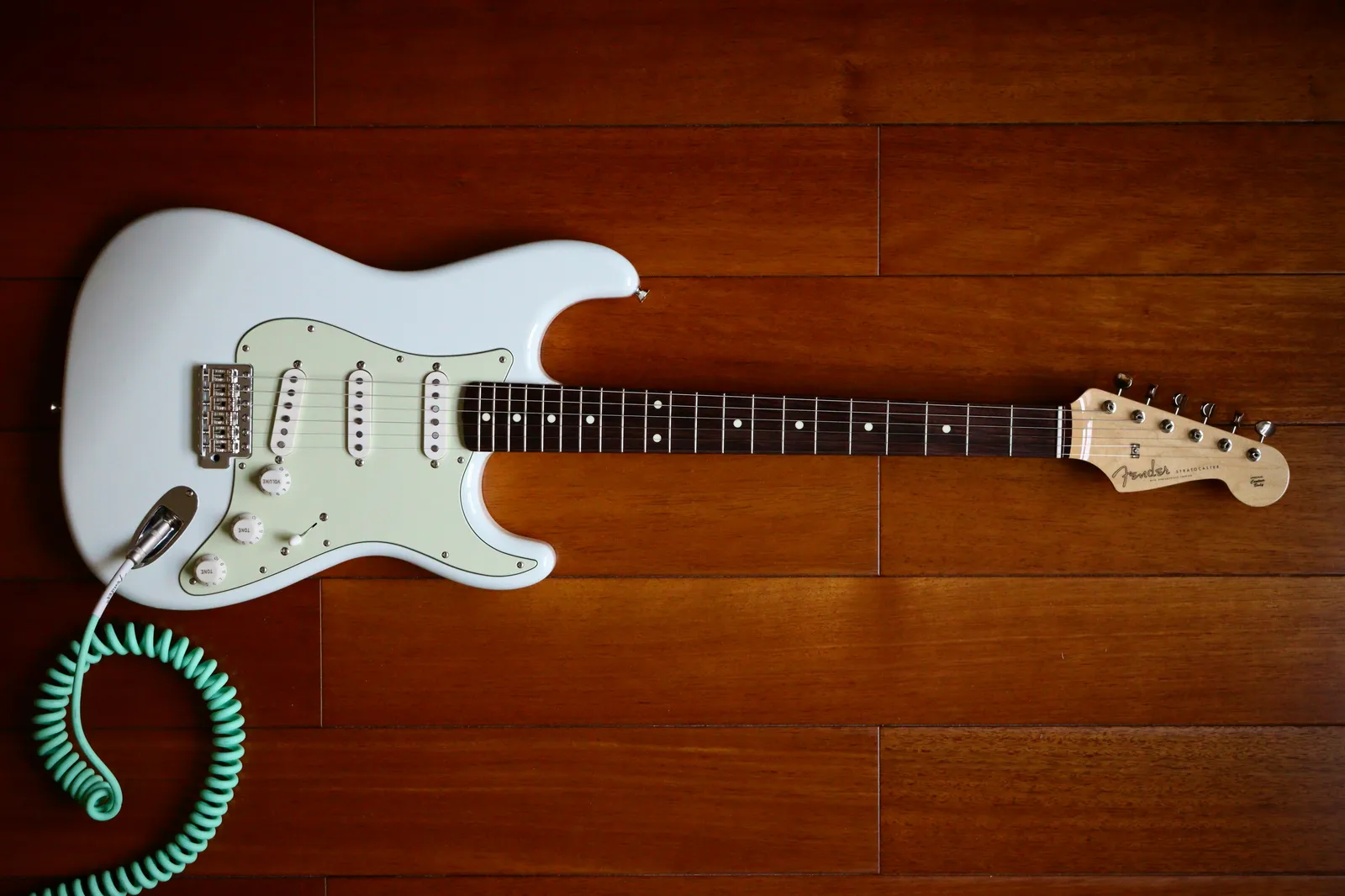 Olympic white Fender Stratocaster resting on a wood floor