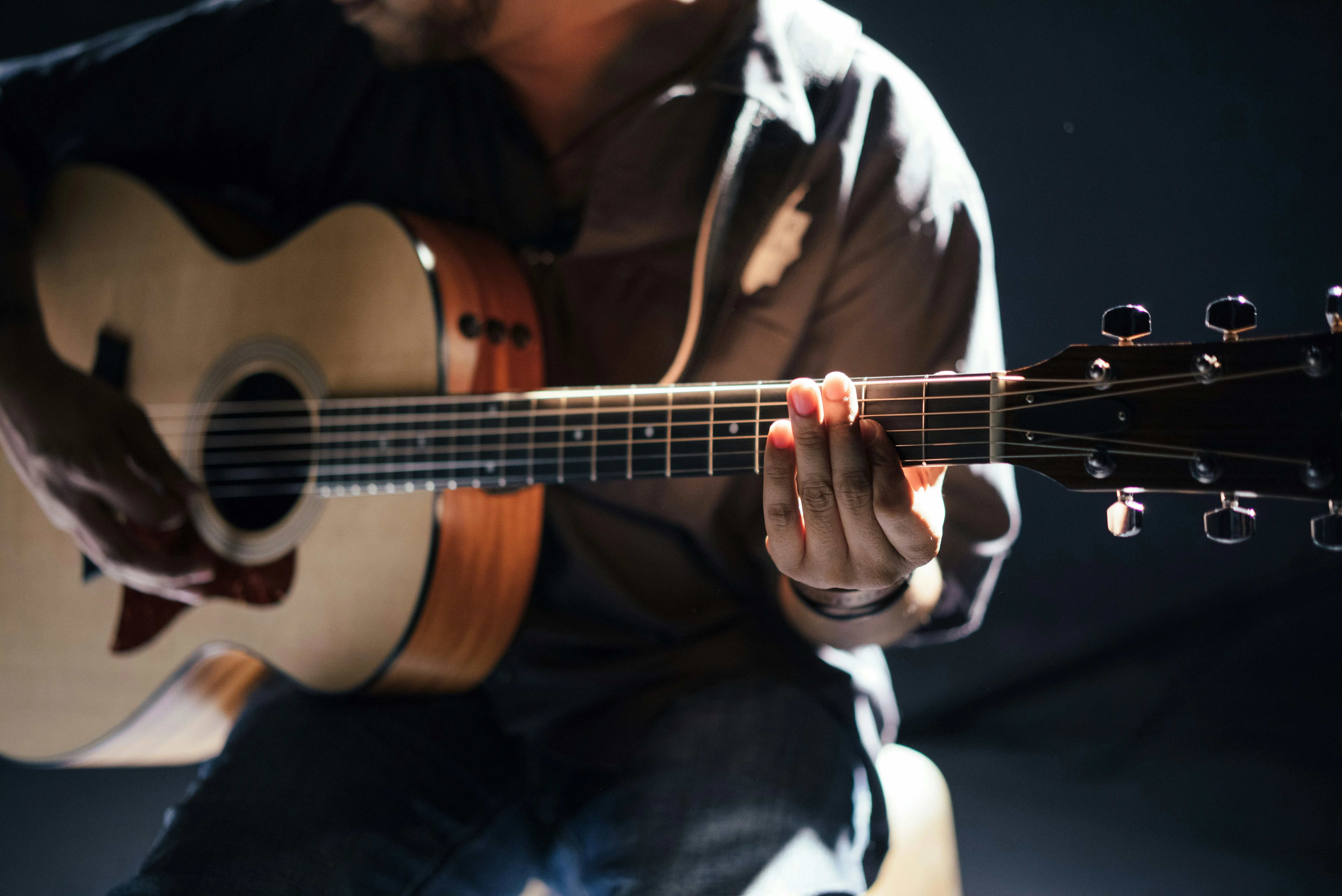 Close-up of hands making a chord position on acoustic guitar — finger placement and anchor technique