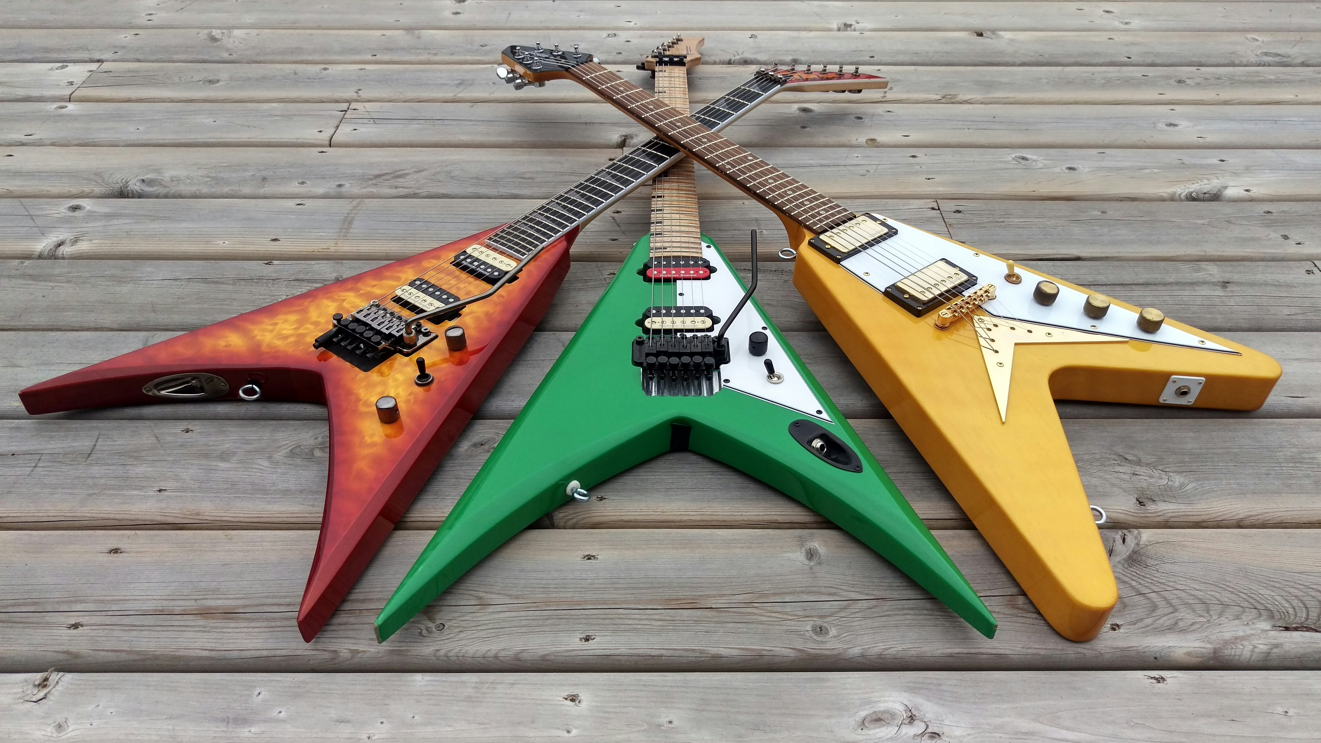 Three Flying V guitars laid out on wood — bold Gibson-style body shapes completely outside the Fender S-style legal controversy