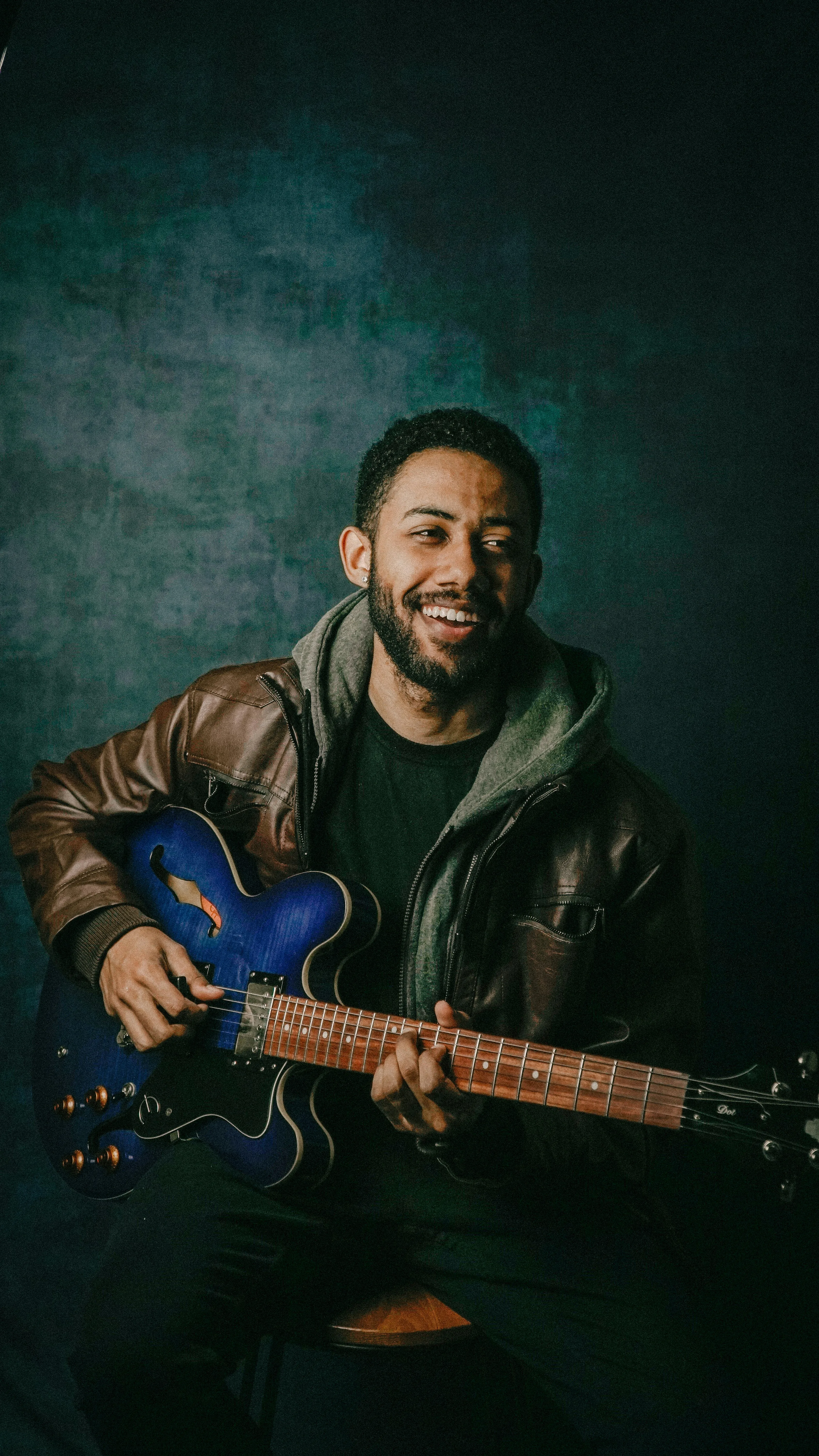 Smiling guitarist holding blue semi-hollow guitar — the moment playing feels natural