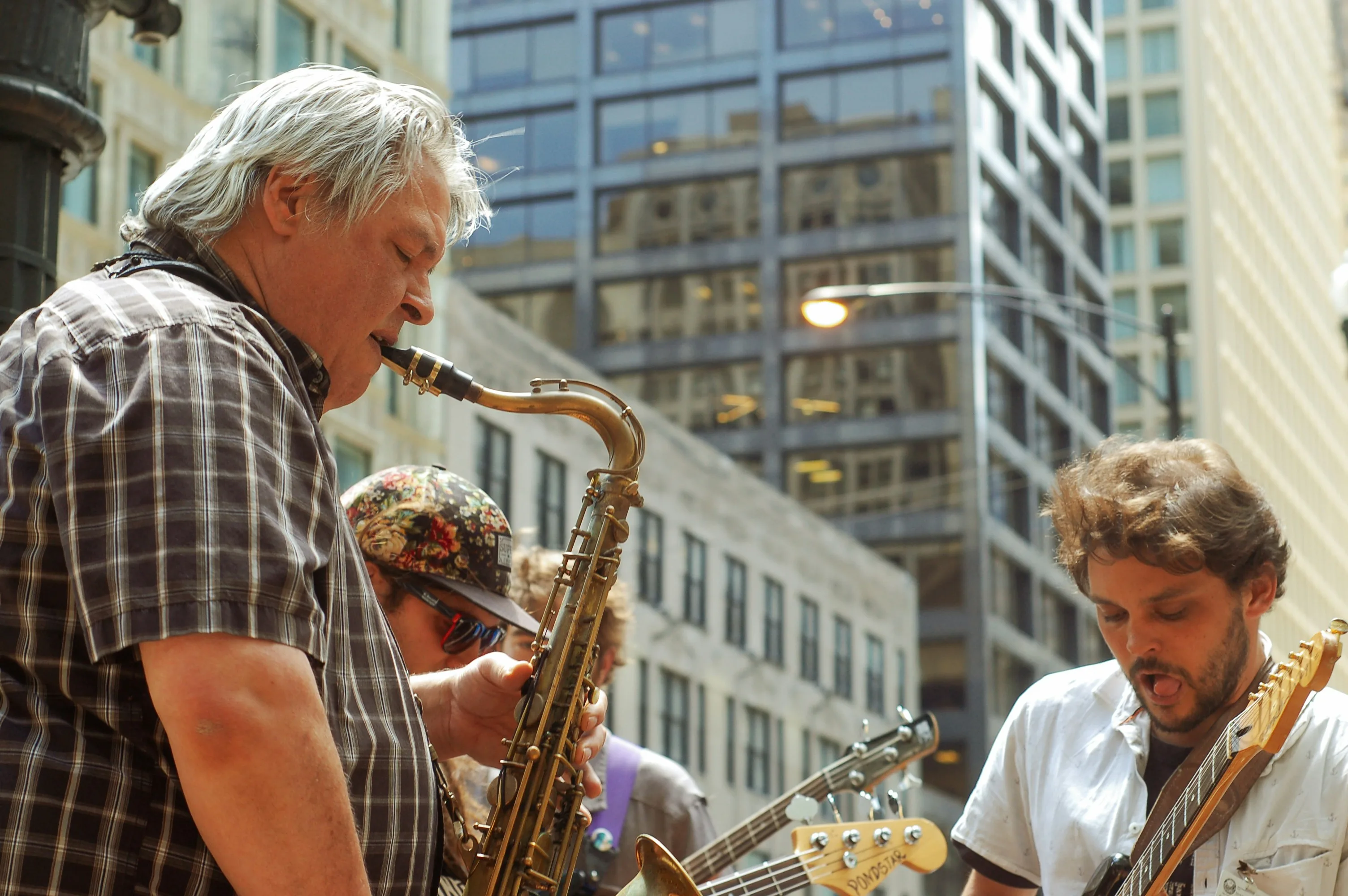 Silver-haired older musician performing outdoors with other players — making music at any age