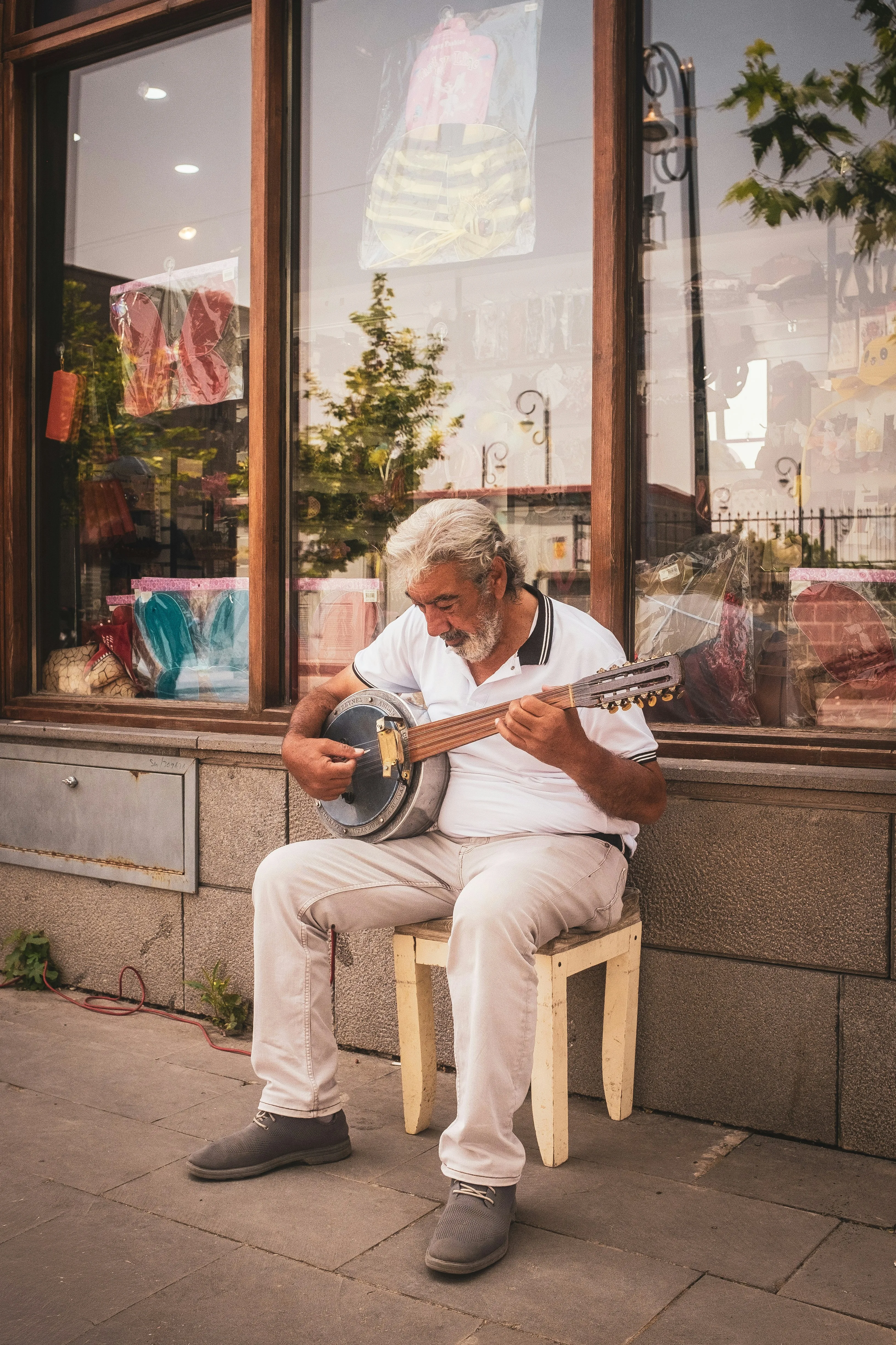 Older man playing guitar casually outside a shop — enjoying music at any age