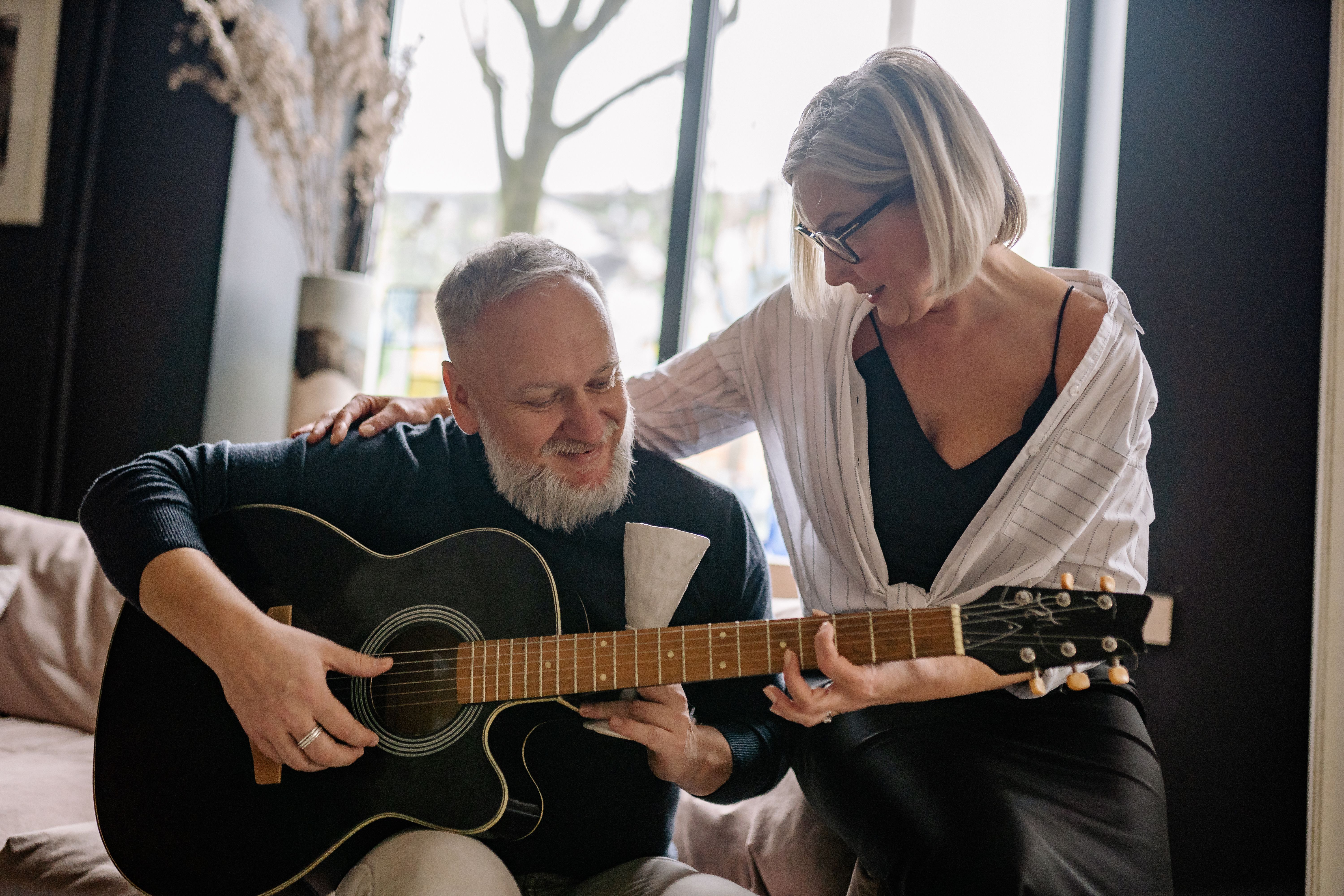 Older adult playing acoustic guitar at home — guitar for seniors guide