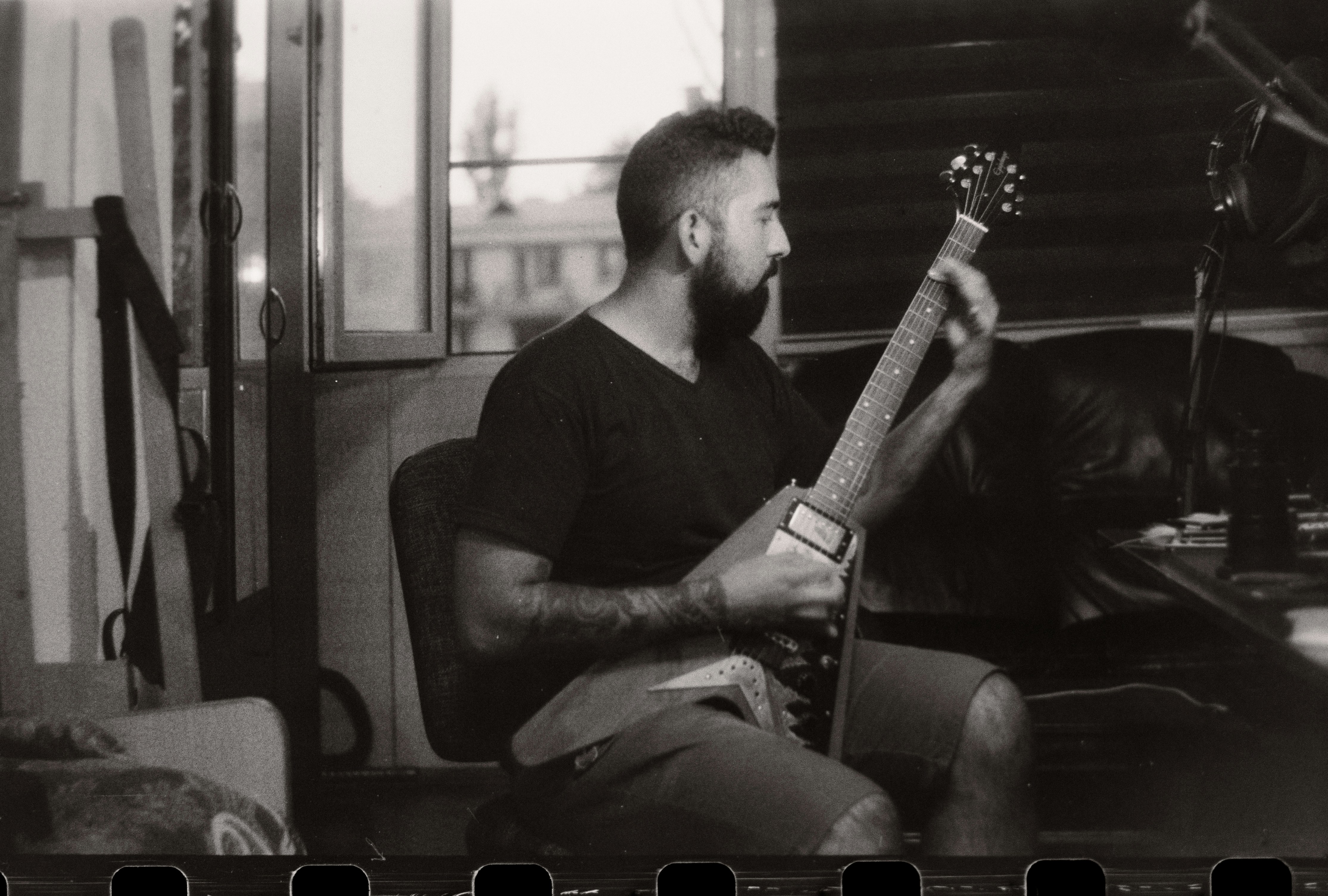 Black and white photo of guitarist playing a Flying V in a studio — the Gibson sound that has nothing to do with Fender's S-style world