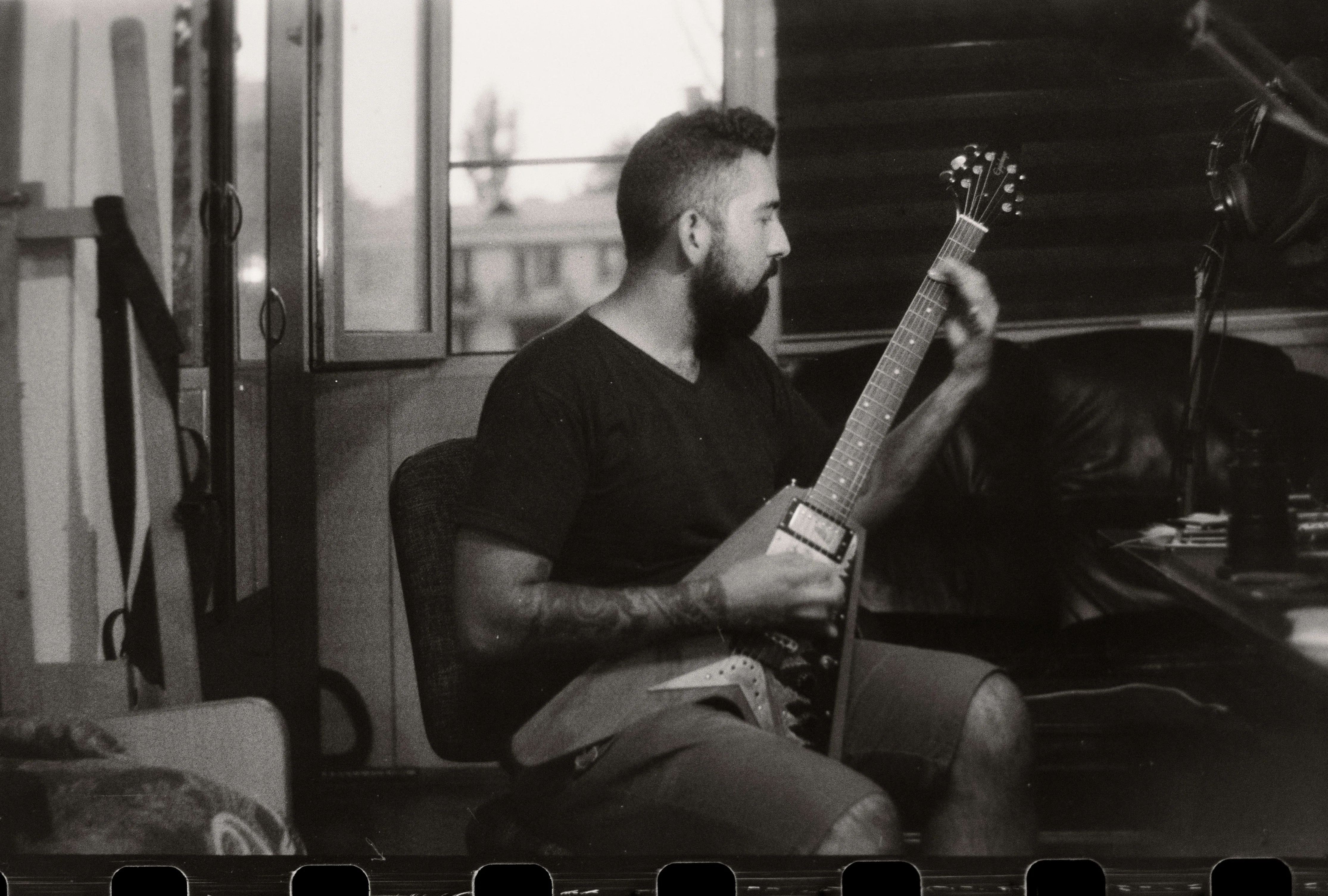 Black and white photo of guitarist playing a Flying V in a studio — the Gibson sound that has nothing to do with Fender's S-style world